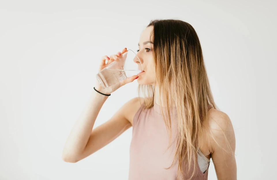 Girl drinking glass of water representing morning hydration before coffee