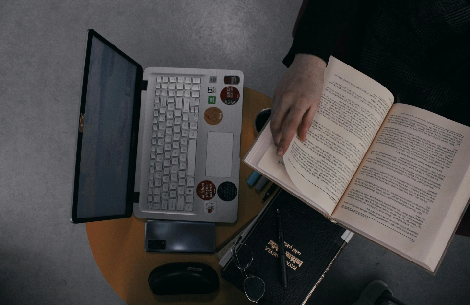 open book next to laptop representing the book vs movie comparison for Remarkably Bright Creatures