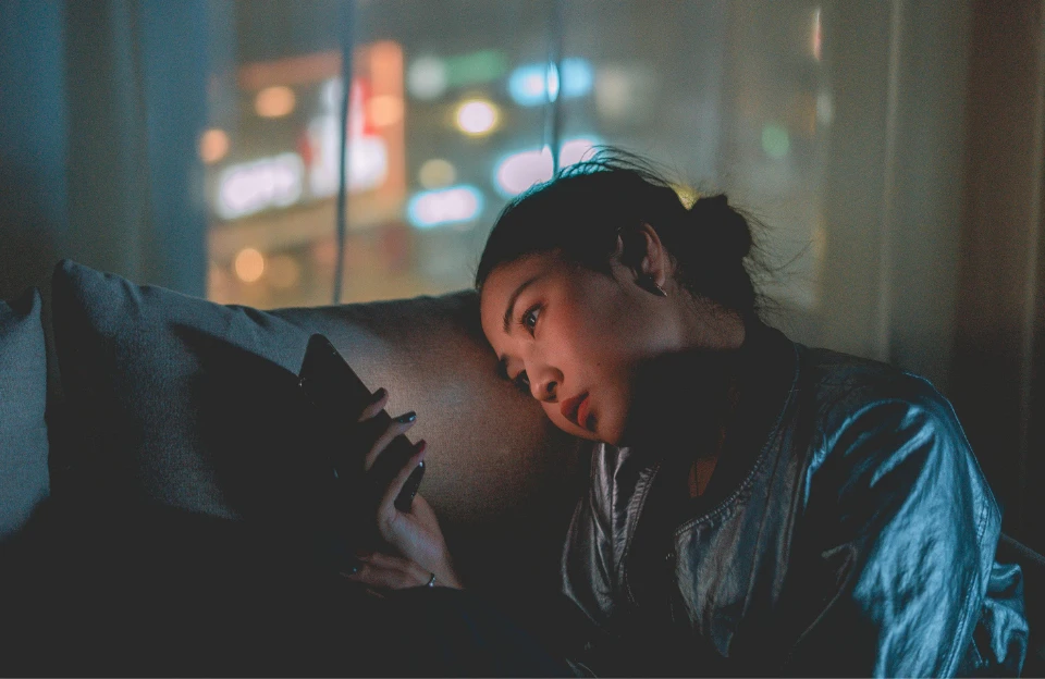 person looking at phone screen in dark room representing themes explored in The Social Dilemma on Netflix